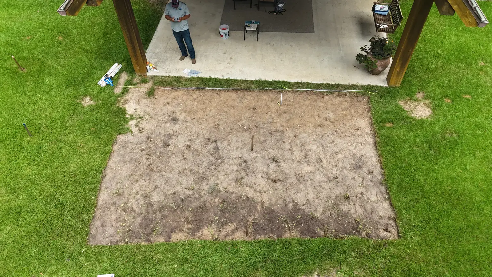 Aerial view of a Houston backyard with the new pool footprint marked and staked on the lawn before excavation begins